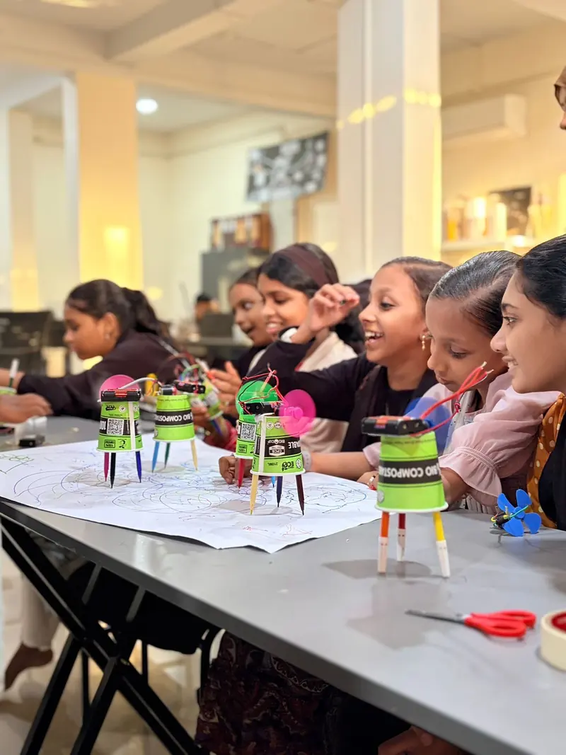 Students watching Scribble Bots draw on paper