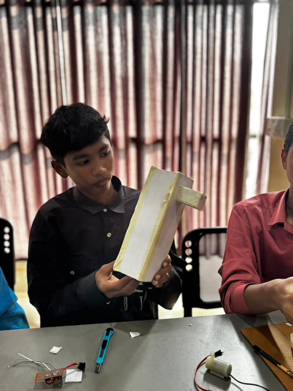 Student cutting out sheets to build the body for the automatic water dispenser